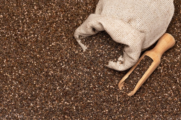 Foto close up de saco de aniagem com sementes orgânicas de chia e colher de madeira