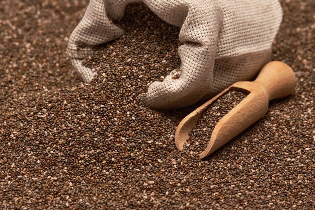 Close up de saco de aniagem com sementes orgânicas de chia e colher de madeira