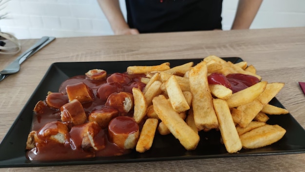 Close-up de salsicha em fatias com batatas fritas na mesa