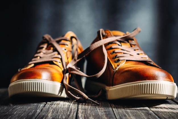 Close-up de sapatos de couro marrom masculino com cadarços no fundo escuro de madeira