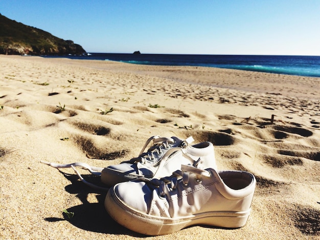 Close-up de sapatos na praia contra o céu limpo