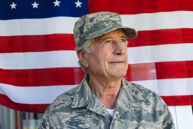 Close-up de soldado do exército caucasiano, vestindo roupas de camuflagem, olhando para longe contra a bandeira da américa