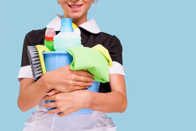 Foto close-up, de, sorrindo, empregada, segurando balde, com, limpeza, equipamento, contra, experiência azul