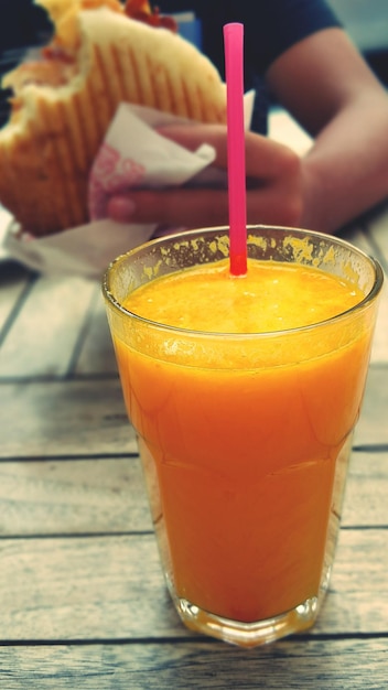 Foto close-up de suco de laranja com um homem comendo hambúrguer