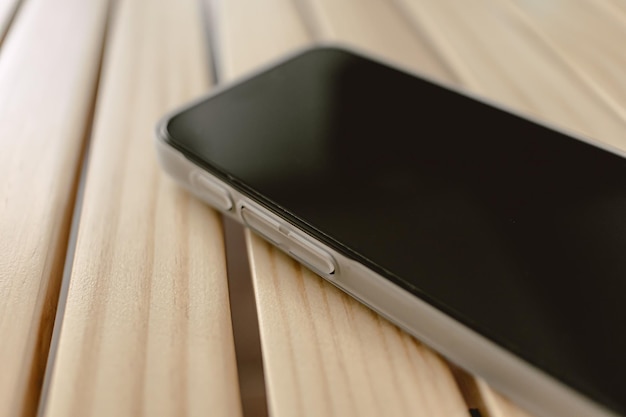 Close-up de telefone móvel usa um estojo matte branco deixado em uma mesa de madeira