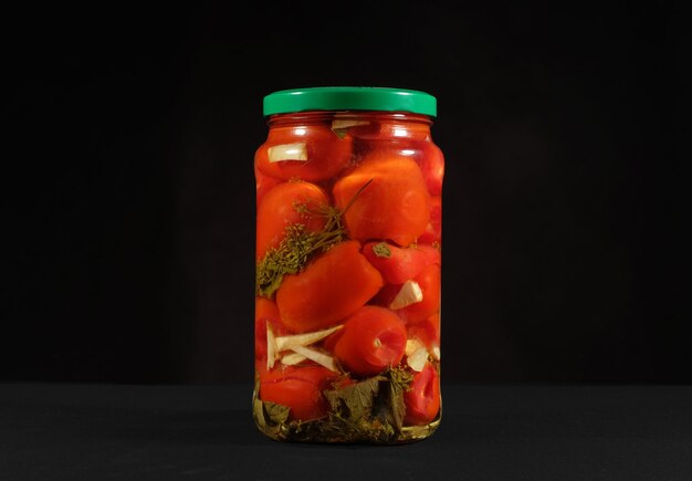 Foto close-up de tomates em frasco contra fundo preto
