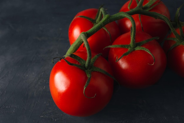 Close-up de tomates maduros vermelhos em fundo escuro Cena escura de tomates frescos com espaço de cópia