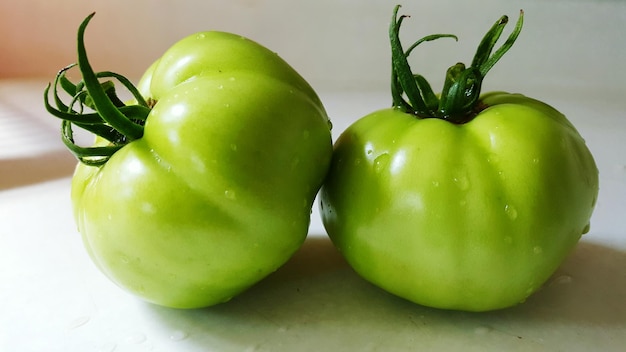 Foto close-up de tomates verdes molhados na mesa