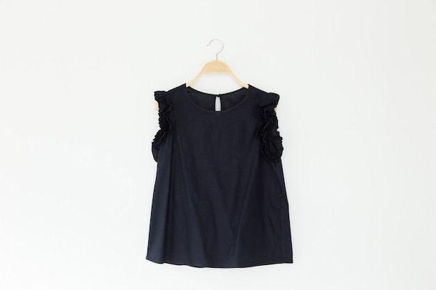 Close-up de top preto em coathanger contra fundo branco