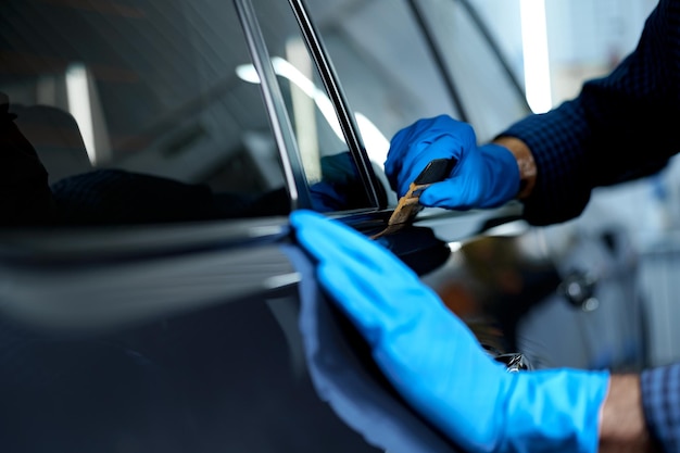 Close-up de trabalhador de serviço de carro masculino aplicando nano revestimento em um carro