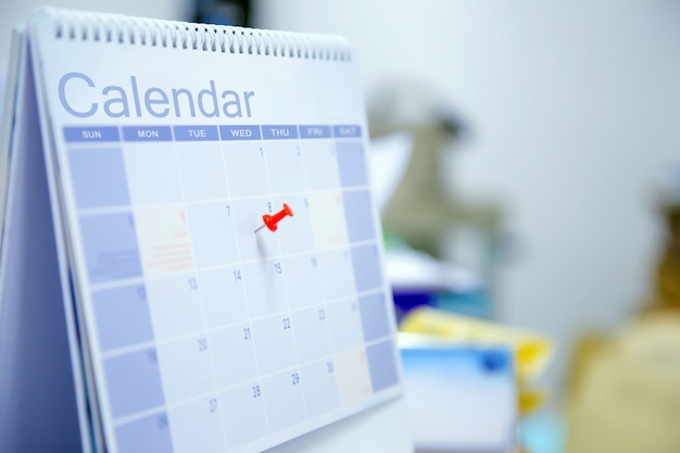 Close-up de um alfinete vermelho no calendário de mesa em branco.