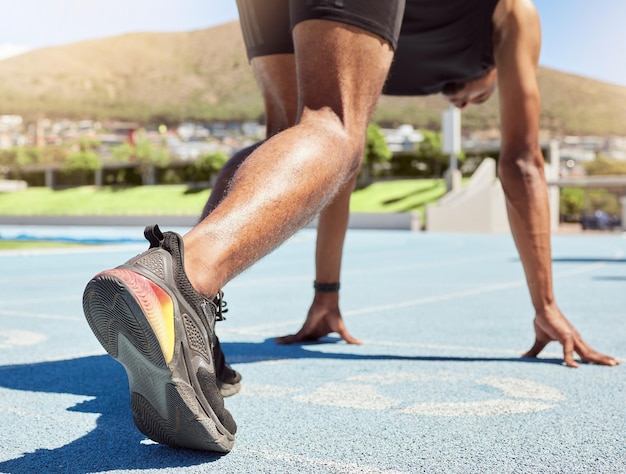 Close-up de um atleta se preparando para correr no atletismo com os pés nos blocos de partida prontos para começar a correr Close-up de um homem na posição inicial para correr uma corrida em uma pista de esportes