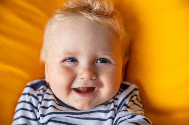 Foto close-up de um bebê de um mês bonito com olhos azuis em um fundo amarelo