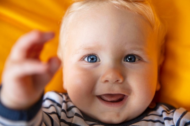 Close-up de um bebê de um mês bonito com olhos azuis em um fundo amarelo