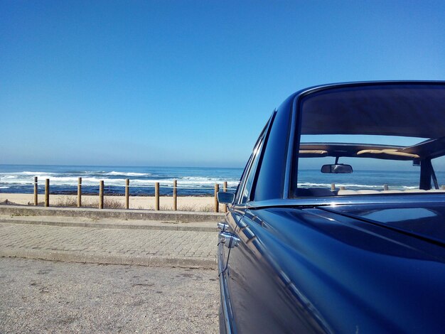 Foto close-up de um carro na praia contra um céu azul claro
