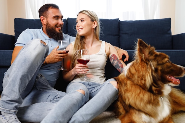 Close-up de um casal bebendo vinho no sofá com seu cachorro border collie perto