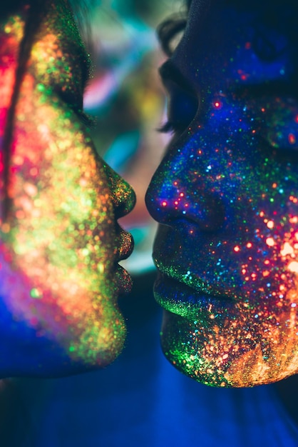 Close-up de um casal beijando com pintura de rosto multicolorida