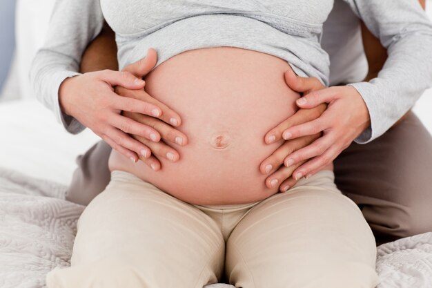 Close up de um casal tocando a barriga da mulher grávida