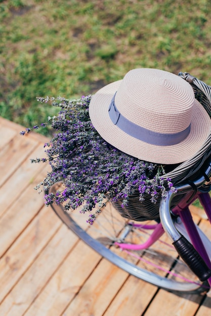 Close-up de um chapéu de palha com flores de lavanda em uma cesta de bicicleta