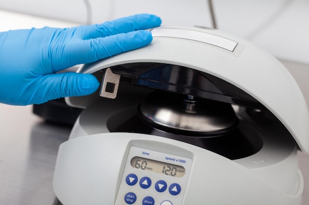 Foto close-up de um cientista fechando uma pequena centrifugadora de mesa cheia de tubos