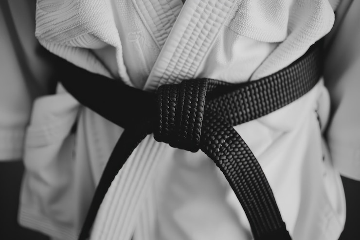 Foto close-up de um cinto preto de jiujitsu amarrado em torno de um kimono branco