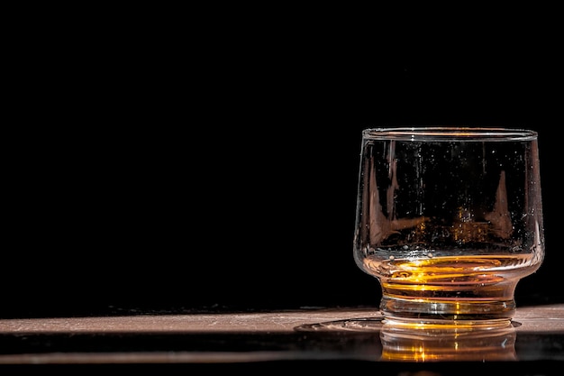 Close-up de um copo de cerveja na mesa contra um fundo preto