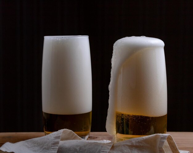 Foto close-up de um copo de cerveja na mesa contra um fundo preto