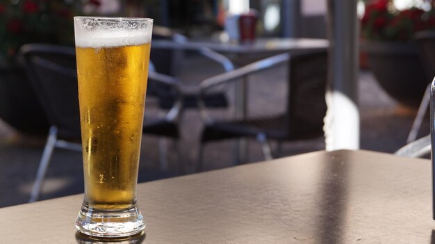 Foto close-up de um copo de cerveja na mesa de um café na calçada