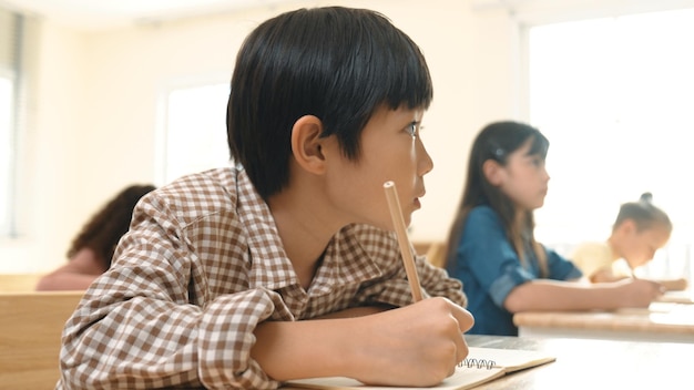 Close-up de um estudante asiático inteligente escrevendo ou fazendo anotações durante um teste de pedagogia