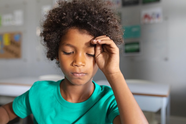 Foto close-up de um estudante primário afro-americano com cabelos rizados na mesa na sala de aula. inalterado, educação, aprendizagem, infância, estudo e conceito escolar.