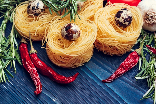 Close-up de um fettuccine italiano seco cru de massa na mesa de madeira azul