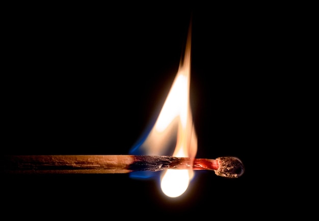 Foto close-up de um fósforo em chamas contra um fundo preto