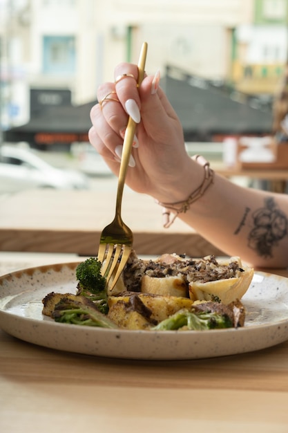 Close up de um garfo na mão de uma mulher sobre um prato com comida deliciosa em um restaurante