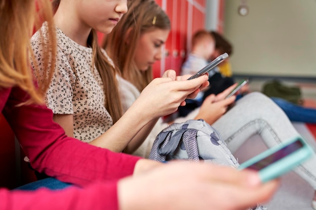 Close-up de um grupo de crianças usando smartphone no corredor da escola