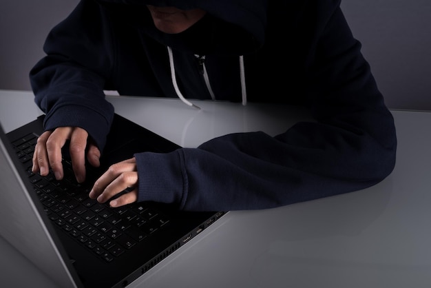 Close-up de um hacker digitando e trabalhando em seu laptop