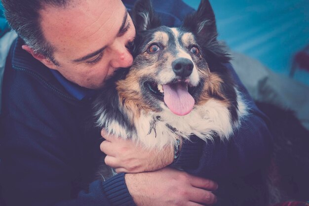 Foto close-up de um homem abraçando um cão na tenda