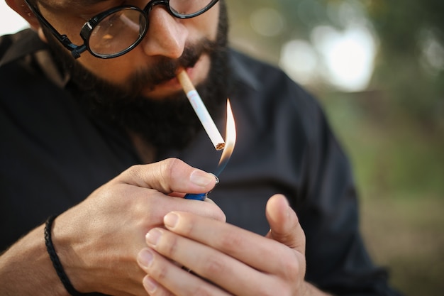 close-up de um homem acendendo um cigarro com um isqueiro