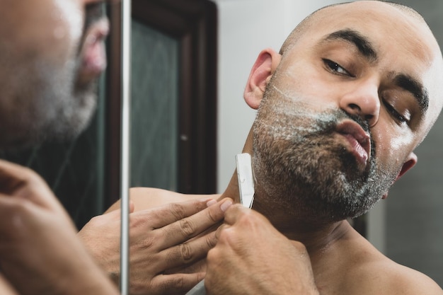 Foto close-up de um homem barbeando-se refletindo no espelho em casa