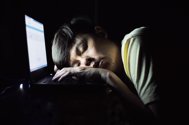 Close-up de um homem cansado dormindo em um laptop em casa