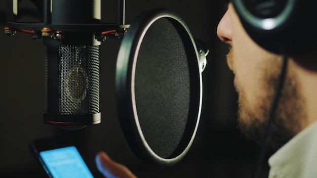 Foto close-up de um homem cantando em um estúdio de gravação