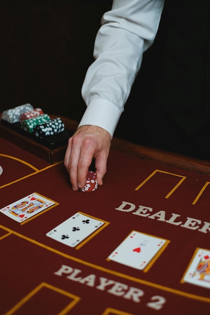 Close-up de um homem colocando fichas de cassino em uma mesa em um jogo de pôquer Foto de estoque