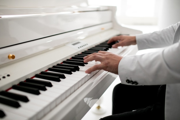 Close-up de um homem com as mãos no piano tocando as mãos de um pianista no teclado de um piano de cauda