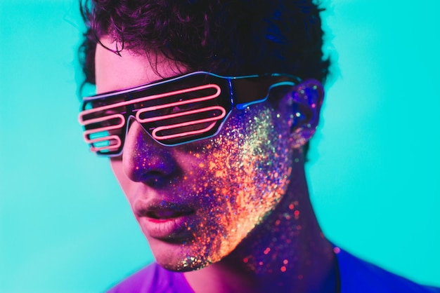 Close-up de um homem com pintura facial multicolorida usando óculos