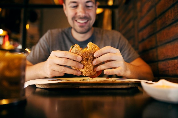 Foto close-up de um homem comendo hambúrguer em um restaurante