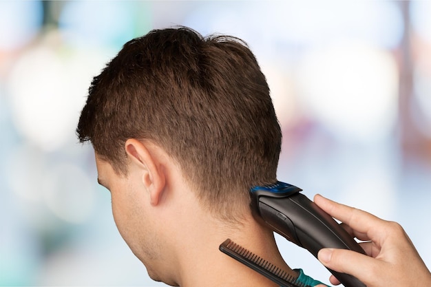 Close-up de um homem cortando o cabelo com máquina de cortar cabelo
