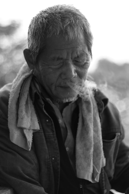 Close-up de um homem idoso emitindo fumaça do nariz