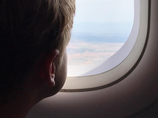 Foto close-up de um homem olhando pela janela de um avião
