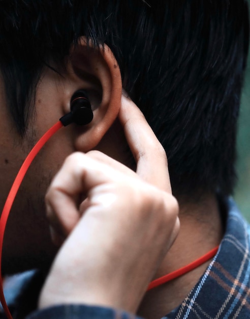 Foto close-up de um homem ouvindo música através de fones de ouvido