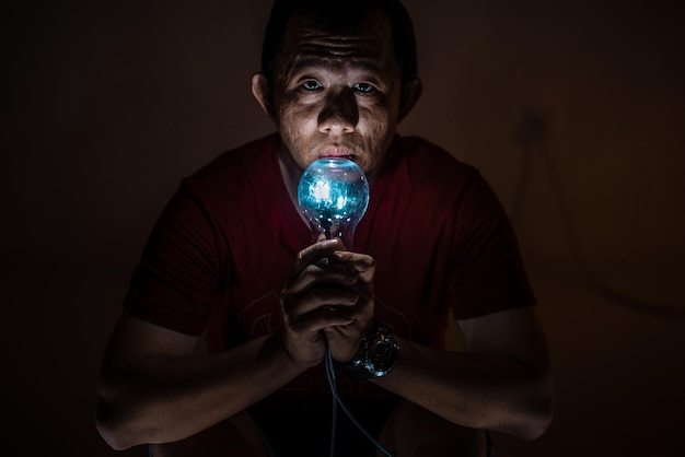 Foto close-up de um homem segurando um equipamento de iluminação iluminado contra a parede