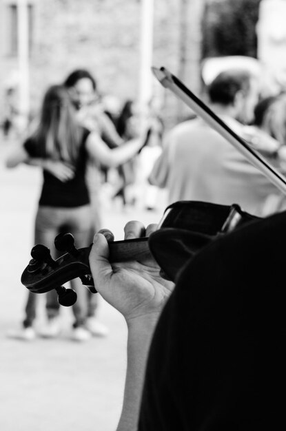 Close-up de um homem tocando violino com um casal dançando ao fundo